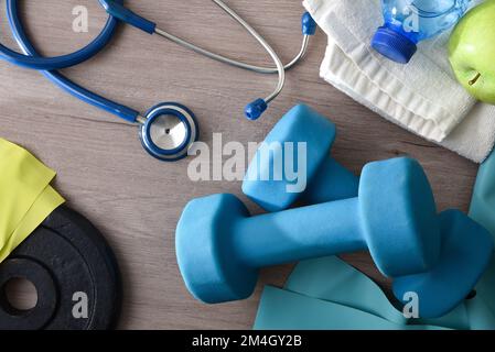 Concept sport et santé avec équipement sportif sur table en bois avec stéthoscope pomme et eau. Vue de dessus. Banque D'Images