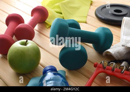 Arrière-plan de l'équipement sportif et la vie saine à la maison sur un plancher en bois avec haltères, poids, élastiques et saine alimentation. Vue en hauteur. Banque D'Images