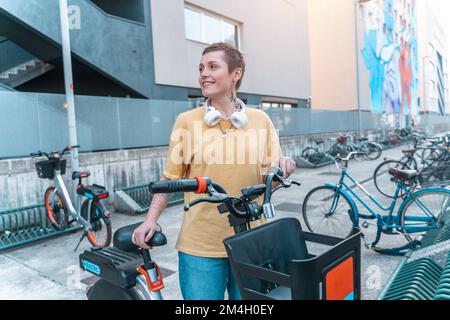 Une femme prend un vélo loué dans un parking à vélos Banque D'Images