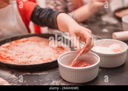 gros plan. les enfants posent les ingrédients sur la base de la pizza Banque D'Images