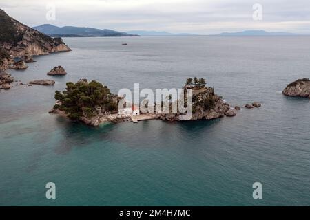 Grèce Parga. Vue aérienne par drone de l'île de Panagia au large de la côte de Parga, petite chapelle et arbres sur le rocher, ciel nuageux. Banque D'Images
