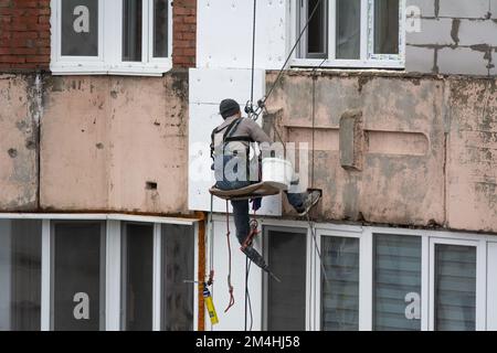 Tiraspol, Moldavie - 10 décembre 2022 : un constructeur de haute altitude isole la façade d'un immeuble d'appartements en plastique mousse. Maison isolante aérée Banque D'Images