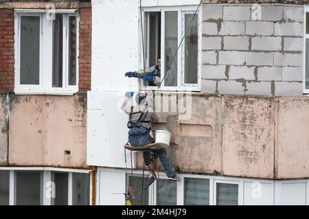 Tiraspol, Moldavie - 10 décembre 2022 : un constructeur de haute altitude isole la façade d'un immeuble d'appartements en plastique mousse. Maison isolante aérée Banque D'Images