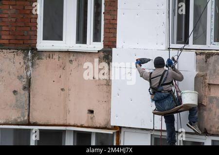 Tiraspol, Moldavie - 10 décembre 2022 : un constructeur de haute altitude isole la façade d'un immeuble d'appartements en plastique mousse. Maison isolante aérée Banque D'Images