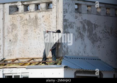 Tiraspol, Moldova - 13 décembre 2022 : le constructeur couvre le toit avec une tôle d'aluminium ondulée. Les travailleurs construisent sur le toit du châssis pour le balcon en décembre. Banque D'Images