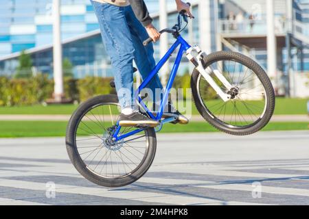 Le cycliste saute sur un vélo sur une aire de jeux dans un parc de la ville, effectuant des tours Banque D'Images