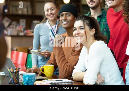 Groupe de personnes travaillant ensemble en équipe sur un projet dans un espace de travail conjoint. Les peuples multiraciaux. Souriant et regardant l'ordinateur portable devant le Banque D'Images