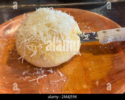 Délicieux pain rond recouvert de parmesan, dans une assiette de beurre fondu. Banque D'Images