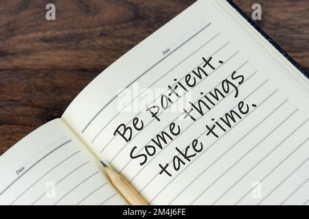 Citations inspirantes sur le bloc-notes avec du texte - soyez patient, certaines choses prennent du temps. Banque D'Images