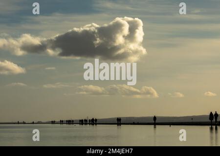 Les marcheurs se sont déambulés contre l'horizon en se promenant autour du lac marin à West Kirby, surplombant l'estuaire de la Dee et la côte nord du pays de Galles Banque D'Images