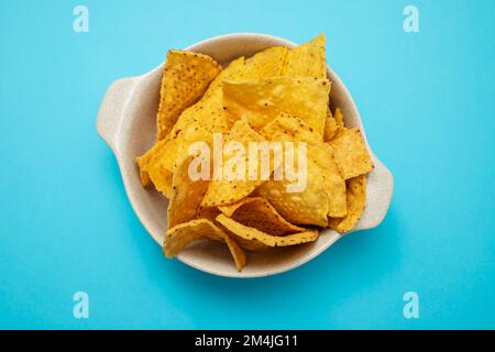 Peu de croustilles de nachos mexicains dans un petit bol sur le bleu Banque D'Images