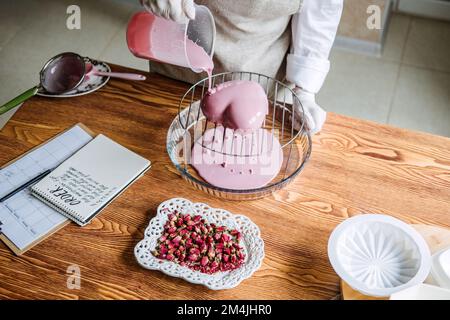 Idées de marketing de la Saint-Valentin pour les petites entreprises. Le chef confiseur fait un coeur rose miroir mousse gâteau Banque D'Images