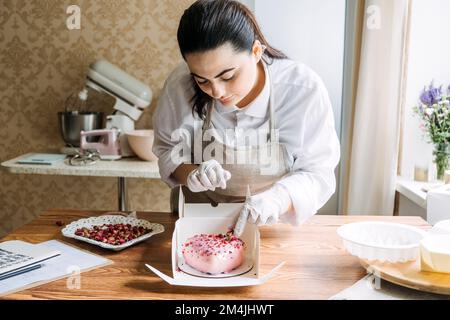 Idées de marketing de la Saint-Valentin pour les petites entreprises. Le chef confiseur fait un coeur rose miroir mousse gâteau Banque D'Images