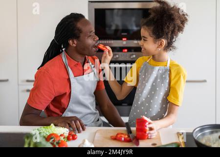 Portrait de père noir aimant et de fille préparant la nourriture dans la cuisine ensemble Banque D'Images