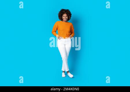 Jolie jeune femme noire posant sur fond bleu studio Banque D'Images