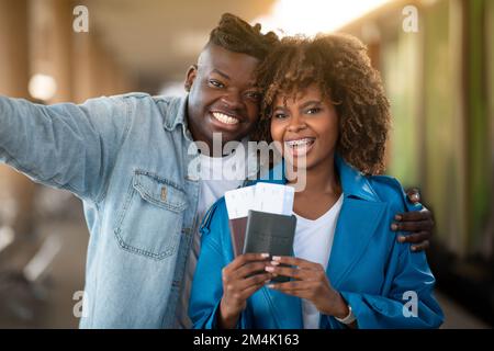 Voyageurs heureux. Un jeune couple noir souriant prend Selfie à la gare Banque D'Images