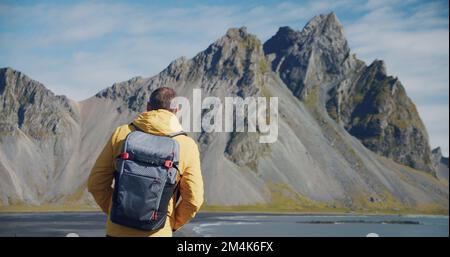 Homme voyageur à la recherche de montagnes fantastiques sur les dunes de sable de lave volcanique sur la plage Stokksness, Islande Banque D'Images