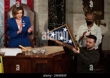 Washington, États-Unis, 21 décembre 2022. Président de la Chambre des représentants des États-Unis Nancy Pelosi (Démocrate de Californie) applaudissent alors que le président ukrainien Volodymyr Zelenskyy détient un drapeau américain qui lui a été présenté par Pelosi à la fin de son discours lors d'une session conjointe du Congrès américain dans la Chambre des représentants du Capitole des États-Unis à Washington, DC mercredi, 21 décembre 2022. Crédit : Cliff Owen/CNP Banque D'Images