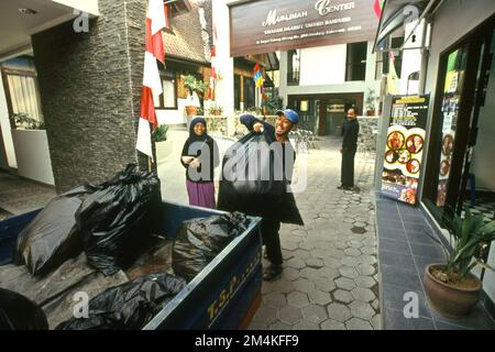 Un homme charge des sacs à ordures en plastique sur un camion stationné près du centre de Daarut Tauhiid et de Managemenet Qalbu, des institutions islamiques fondées par un célèbre prédicateur islamique indonésien, KH Abdullah Gymnastiar, situé à Gegerkalong, Bandung, West Java, Indonésie. Gymnastiar (connu sous le nom de AA Gym), Daarut Tauhiid, et leur direction Manajemen Qolbu (MQ), ont réussi à l'escalade du tourisme religieux et des activités économiques dans la région de Gegerkalong à Bandung City. Banque D'Images