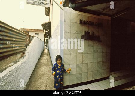 Portrait d'un enfant devant une mosquée située dans un quartier dense près de Gegerkalong, à Bandung, Java-Ouest, Indonésie. Banque D'Images