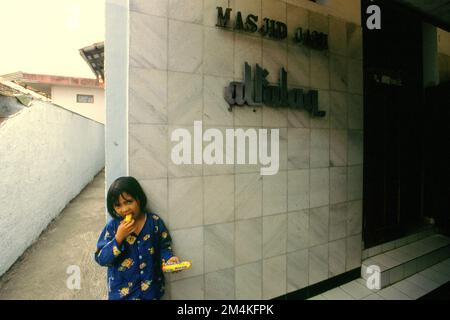 Portrait d'un enfant devant une mosquée située dans un quartier dense près de Gegerkalong, à Bandung, Java-Ouest, Indonésie. Banque D'Images