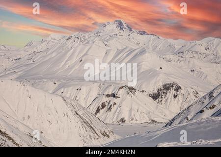 Le sommet du Mont Kazbek sous le ciel orange du soir avec les montagnes du Caucase couvertes de neige, Gudauri Banque D'Images