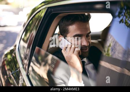 Bien sûr, nous pouvons nous rencontrer quand vous le souhaitez. un beau jeune homme d'affaires qui fait un faux-téléphone tout en se rendant au travail le matin. Banque D'Images