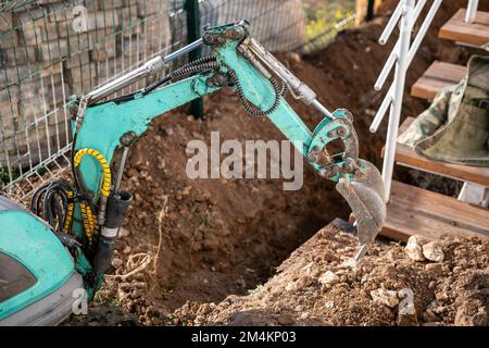 Une minipelle creuse une tranchée pour poser les tuyaux. Gros plan d'une pelle hydraulique creusant une tranchée profonde. Une pelle hydraulique creuse une tranchée dans la campagne pour déposer un Banque D'Images