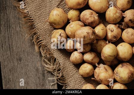 les jeunes pommes de terre pelées aux cheveux rouges se trouvent sur une table en bois Banque D'Images