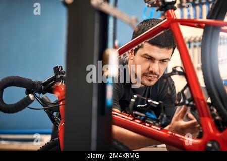 Il connaît ses bicyclettes. un homme travaillant dans un atelier de réparation de vélos. Banque D'Images