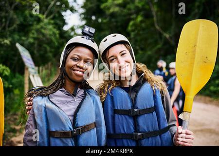 Nous devrions le faire plus souvent. Portrait de deux jeunes femmes gaies portant un équipement de protection tout en tenant une rame dehors pendant la journée. Banque D'Images