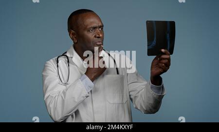 Mature sérieux homme radiologue médecin examinant les résultats de la vérification des rayons X scanner regardant pensive et focalisé bouleversé homme médecin expert analyse la blessure Banque D'Images