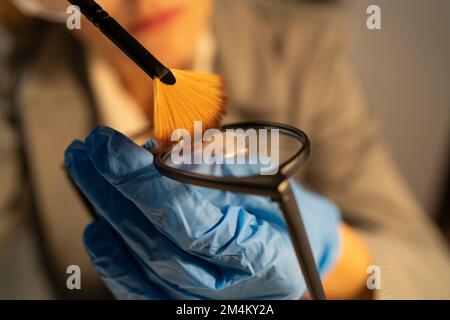 Analyse légale des empreintes digitales, la femme criminaliste recueille les empreintes latentes à l'aide de poudre sur les lunettes de preuve, en copiant les empreintes digitales sur l'élévateur. Copie s Banque D'Images