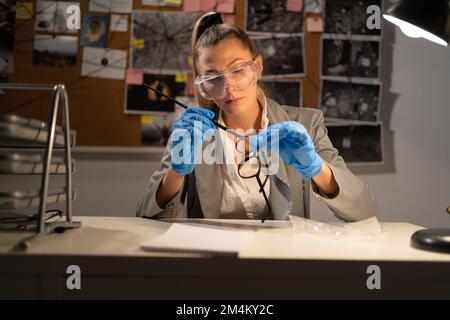 Scientifique légiste dame examinant les lunettes de preuve de la scène du crime. Copier l'espace Banque D'Images