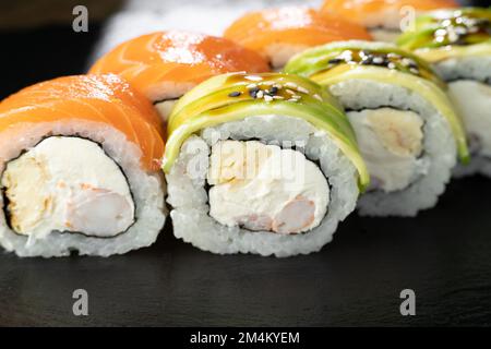 Gros plan de Rainbow Sushi Roll avec saumon, avocat, crevettes royales, fromage à la crème Philadelphia, chuka. Menu sushi. Concept alimentaire japonais. Banque D'Images