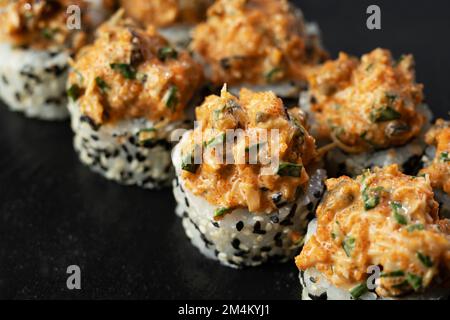 Ensemble de petits pains à sushis frais au saumon, à l'avocat, aux moules et aux graines de sésame noir servis sur une ardoise de pierre noire. Sushis japonais uramaki ou rouleau californien Banque D'Images