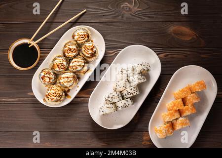 Petits pains à sushis servis dans une assiette blanche japonaise traditionnelle. Sur fond de bois, vue de dessus. Copier l'espace Banque D'Images