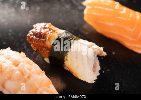 Sushi nigiri au saumon, au mérou, à l'anguille, au thon et à la crevette sur ardoise noire. Délicieux plats japonais traditionnels, fruits de mer savoureux, concept de restaurant Banque D'Images