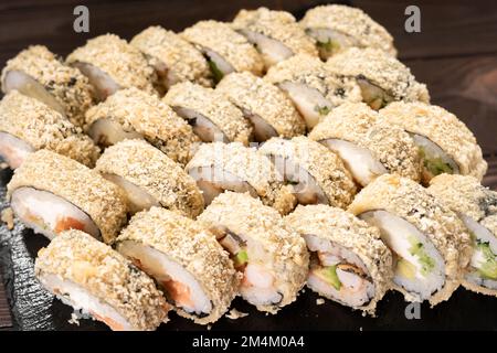 Roulé à sushis frits chauds avec saumon et anguille. Menu sushi. Cuisine japonaise. Rouleau de sushi frits chauds sur un tableau noir en ardoise. Vue de dessus Banque D'Images