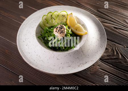 Cuisine japonaise, salade d'algues Goma Wakame avec sauce aux noix dans une assiette blanche sur fond de table. Vue de dessus Banque D'Images