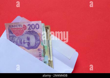 La hryvnia ukrainienne en dénomination de 200 se trouve dans une enveloppe blanche sur un fond rouge gros plan Banque D'Images