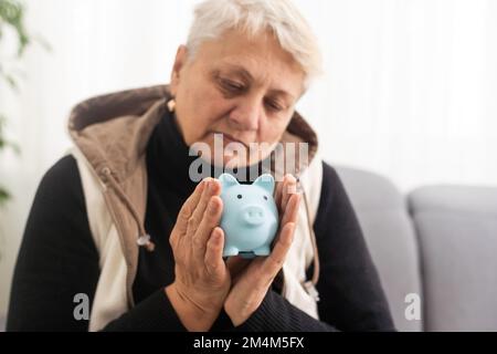 Gros plan d'une femme âgée tenant une caisse d'argent de porc. Femme âgée mains tenant une porcgybank. Concept d'économie d'argent pour les personnes âgées. Banque D'Images