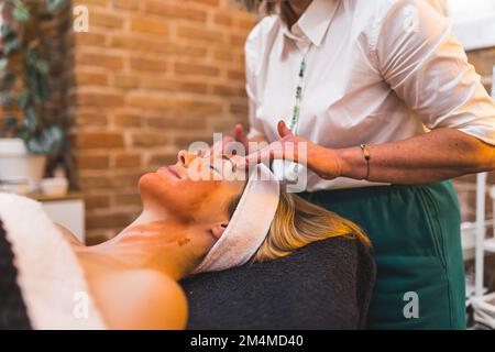 Portrait intérieur d'une femme de race blanche pendant la procédure faciale. Jeune femme adulte détendue pendant le massage du visage. Photo de haute qualité Banque D'Images