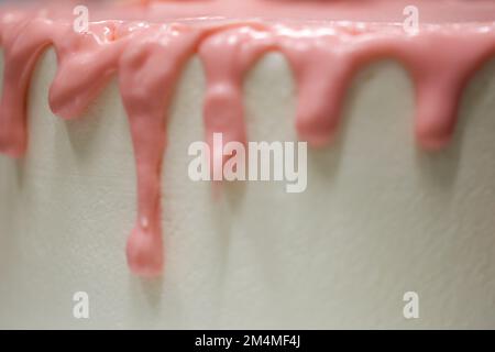 chef cuisinier de gâteau préparant un goutter rose sur un gâteau blanc dépoli pour la fête d'anniversaire de petite fille au laboratoire de cuisine Banque D'Images