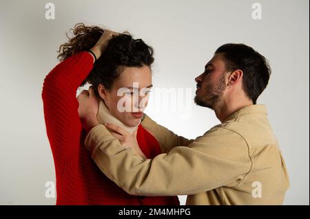 Une femme portant un corset de cou, assistée par un homme sur un fond blanc et gris isolé Banque D'Images