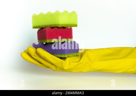 Pile d'éponges de lave-vaisselle multicolores éclatantes dans la main de femme dans un gant de protection. Tampon à récurer pour le nettoyage ménager. Concept de nettoyage à domicile. Espace pour le texte. Banque D'Images