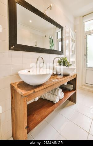 une salle de bains avec deux lavabos et un grand miroir sur le mur derrière elle est une porte ouverte qui mène à un patio Banque D'Images