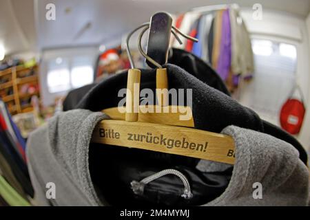 22 décembre 2022, Saxe-Anhalt, Halberstadt: Un cintre avec l'inscription 'Please return' est accroché sur un porte-vêtements au magasin de vêtements Caritasverband à Halberstadt. Dans le district de Harz, il y a des magasins de vêtements qui aident beaucoup de gens à couvrir un approvisionnement de base de vêtements et de chaussures. En raison de la situation actuelle et du sort froid, beaucoup plus de personnes dépendent actuellement de ce soutien que d'habitude. Par conséquent, les chambres à vêtements du district sont vides. Par conséquent, les sponsors des chambres de vêtements continuent de demander du soutien: Bien conservé vêtements chauds aussi bien que chauds Banque D'Images