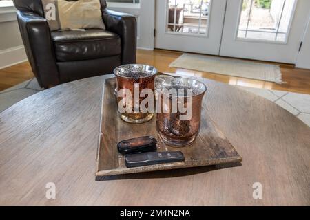 Une paire de bougies assorties placées sur un plateau avec des télécommandes sur une table basse comme décoration d'intérieur dans un salon Banque D'Images