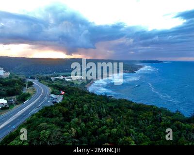 Une prise de vue aérienne au-dessus d'une mer, d'arbres tropicaux et d'une autoroute dans la ville de Quebradillas, Porto Rico Banque D'Images